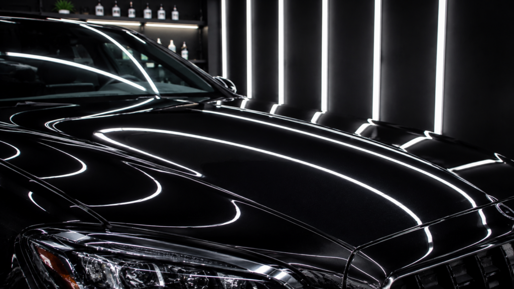 Close-up of black luxury car paint with flawless gloss and scratch-free surface in a detailing studio.