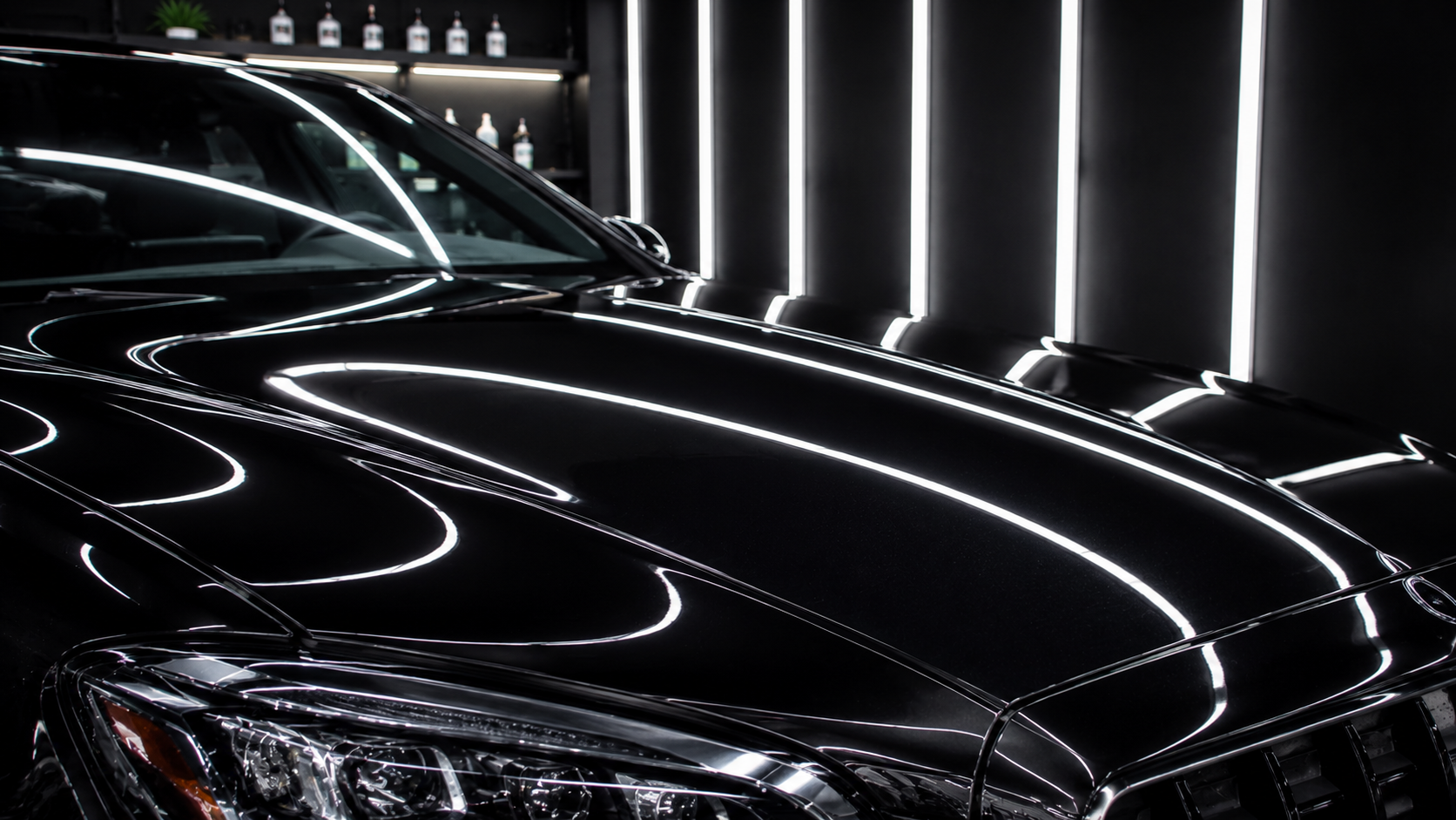 Close-up of black luxury car paint with flawless gloss and scratch-free surface in a detailing studio.